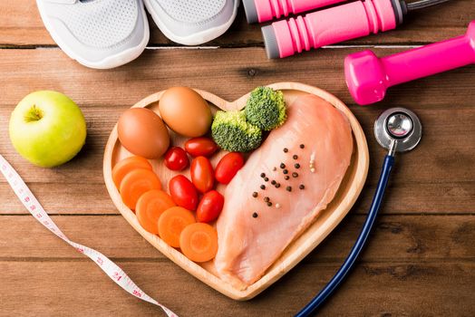 Top view of Raw chicken breasts fillets no boneless with spices in heart plate wood and sport or athlete's equipment dumbbell
running shoes on wooden background, Healthy lifestyle diet food concept