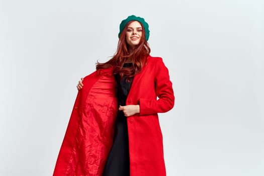 Portrait of a woman in a red coat and in a green hat dark clothes light background model cropped view. High quality photo