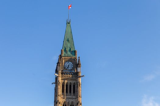 The Peace Tower, which stands in the middle of Centre Block in Ottawa's Parliament Hill, is seen against a blue sky from below.