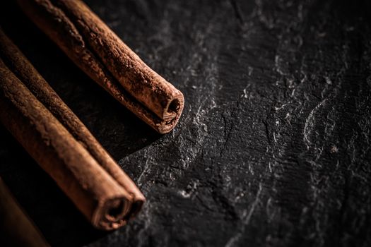 Cinnamon sticks on black stone background, food recipes