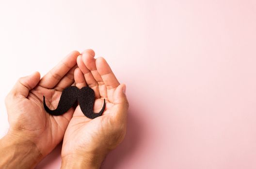 The man uses hand holding black mustache, studio shot isolated on white background, Prostate cancer awareness month, Fathers day, minimal November moustache concept