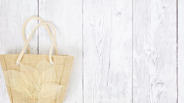 Hessian bag covered with transparent leaves flat lay timber backdrop with copy space for your text