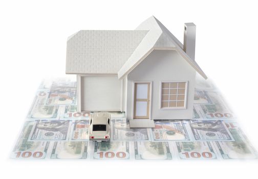 House miniature with white car on US dollar bills isolated in white background for real estate and construction concepts. House miniature designed and created by contributor
