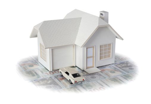 House miniature with white car on US dollar bills isolated in white background for real estate and construction concepts. House miniature designed and created by contributor