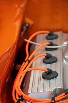 Close up of spark plug leads in engine of orange custom classic vintage car