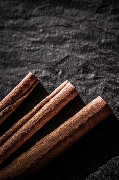 Cinnamon sticks on black stone background, food recipes