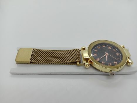 golden colored watch closeup on gray background