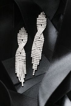 Luxury diamond earrings on black silk ribbon as background, jewelry and fashion brands