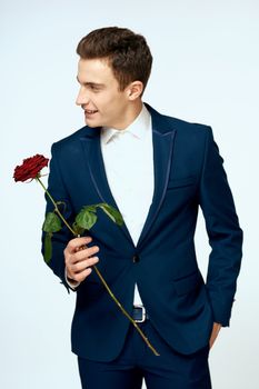 A man in a suit with a rose in his hands a gift date light background. High quality photo