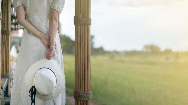 Woman in white dress walking on Bamboo tunnel and bridge as the walk way through the rice field.