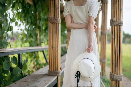 Woman in white dress walking on Bamboo tunnel and bridge as the walk way through the rice field.