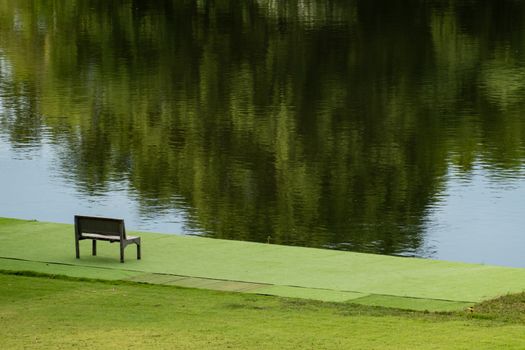 Wooden chair near river and green view.