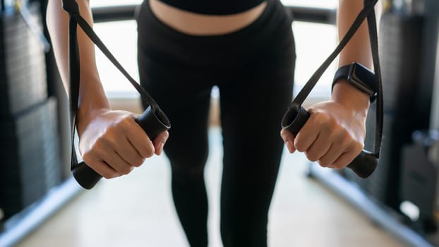Woman arms doing cable fly exercise in gym.