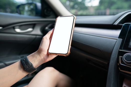 Image of hand holding mobile phone with mockup white screen in car.