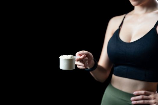 Close up of women hand holding measuring scoop of whey protein preparing protein shake.
