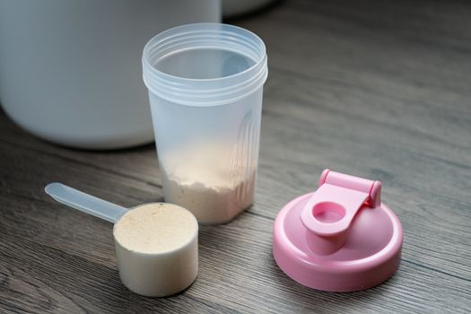 Close up of whey protein with measuring scoop and bottle preparing protein shake.
