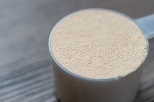 Whey protein powder with measuring Scoop, sports bodybuilding supplement.