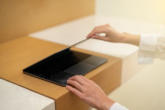 Woman hand open or close laptop on wood table.