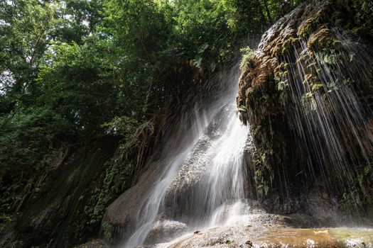 Waterfall in tropical rainforest with rock and sunlight. Saiyok noi Waterfall, Located in Kanchanaburi province, Thailand.