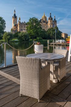 Empty chairs in outdoor cafe or restaurant on summer day with a beautiful fairytale castle in Schwerin in the background.