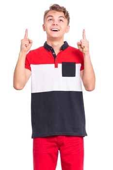 Portrait of surprised teen boy pointing fingers up at copyspace, isolated on white background. Teenager pointing finger at something. Cute amazed child looking away.