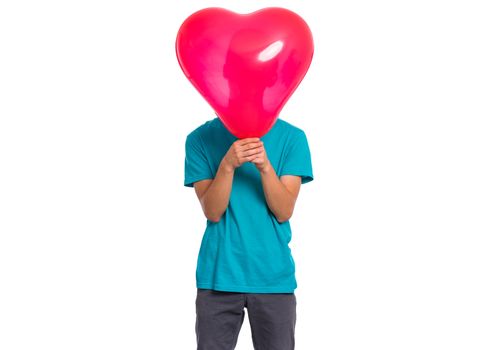 Teen boy hiding behind red heart shaped balloon. Child holding symbol of love, family, hope. Celebration of Saint Valentines Day. Teenager cover face isolated on white background.