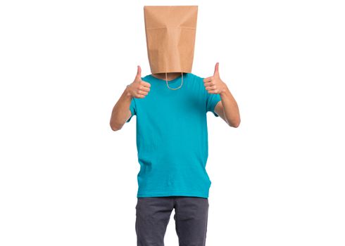 Portrait of teen boy with paper bag over head making thumb up gesture, isolated on white background. Child showing success sign.