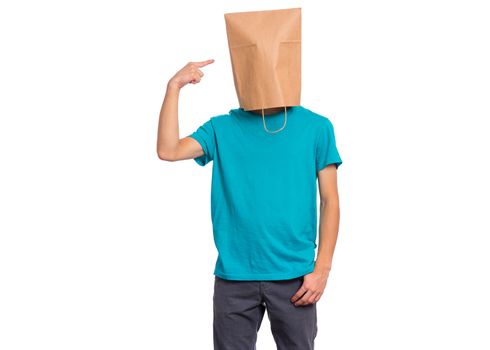 Portrait of teen boy pointing finger at paper bag over head, isolated on white background. Child posing in studio.