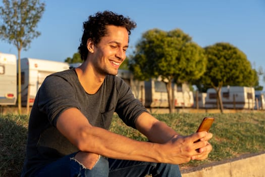 Portrait of young man using the mobile phone in the park with beautiful sunset