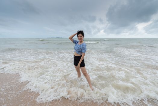 Asian beautiful girl has felt happy on the beach with a cloudy sky.