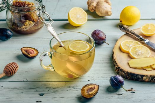 Cup of tea with lemon, honey and ginger over wooden surface