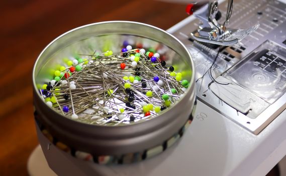 A can full of colorful pins on a sewing machine