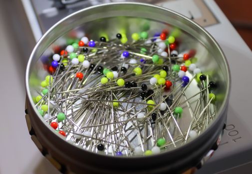 A can full of colorful pins on a sewing machine