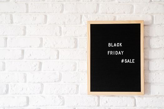 Black friday, seasonal sale concept. Text black friday sale on black letter board on white brick wall with copy space