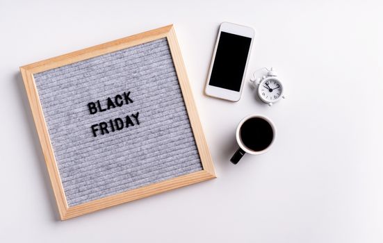 Black friday, seasonal sale concept. Text black friday on gray letter board with mobile phone, coffee and alarm clock on white background