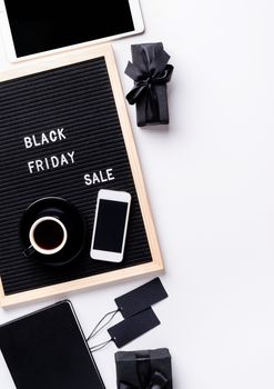 Black friday, seasonal sale concept. Text black friday sale on black letter board with cup of coffee, smarfphone, price tags on white background