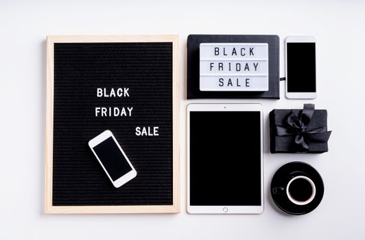 Black friday, seasonal sale concept. Text black friday sale on black letter board with cup of coffee, smarfphone, price tags on white background