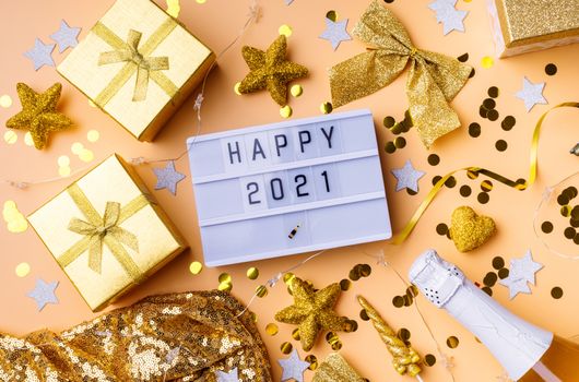 New Year and Christmas flat lay. Lightbox with the words Happy 2021 top view on yellow background with confetti and decorations flat lay