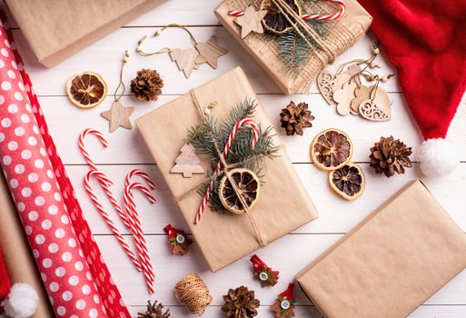 Christmas gifts wrapping. Gift boxes wrappaed in craft paper decorated with pine cones, candy canes and fir tree branches top view flat lay