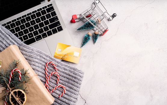 Christmas planing, online shopping concept. Top view of laptop, christmas decorations and shopping cart on white background. Christmas online shopping