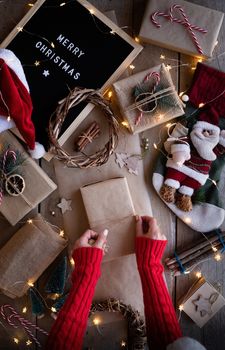 Zero waste and eco friendly christmas concept. Female hands wrapping christmas gifts in craft paper top view flat lay