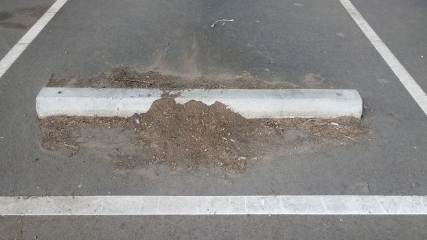 cement curb with debris in parking space or lot with asphalt