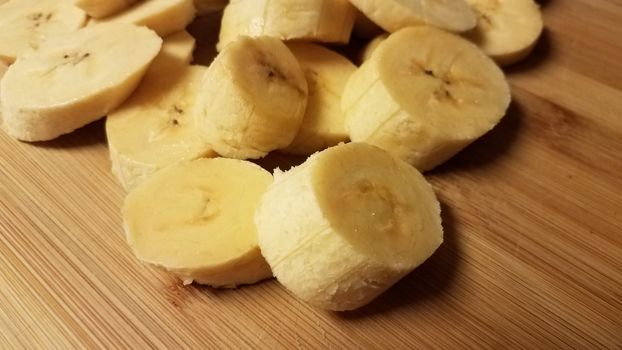 sliced plantain banana fruit on wood cutting board