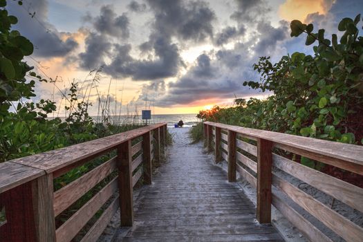 Lone man on a Boardwalk leading toward Delnor-Wiggins State Park at sunset in Naples, Florida.
