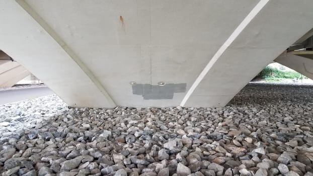 paint under a bridge column with rocks or stones