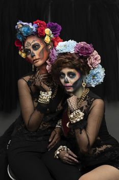 Female models with a sugar skull makeup dressed with flower crown. Halloween concept