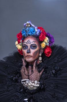 Closeup portrait of a woman with a sugar skull makeup dressed with flower crown. Halloween concept