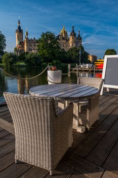 Empty chairs in outdoor cafe or restaurant on summer day with a beautiful fairytale castle in Schwerin in the background.