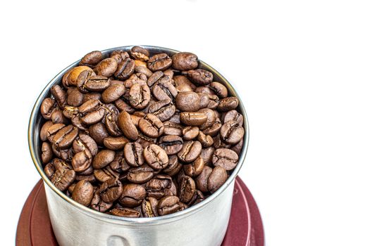 A lot of coffee beans in a metal coffee grinder on a white background. Isolated coffee items