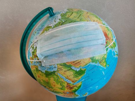 Disinfecting face mask on the globe of the planet Earth.Texture or background